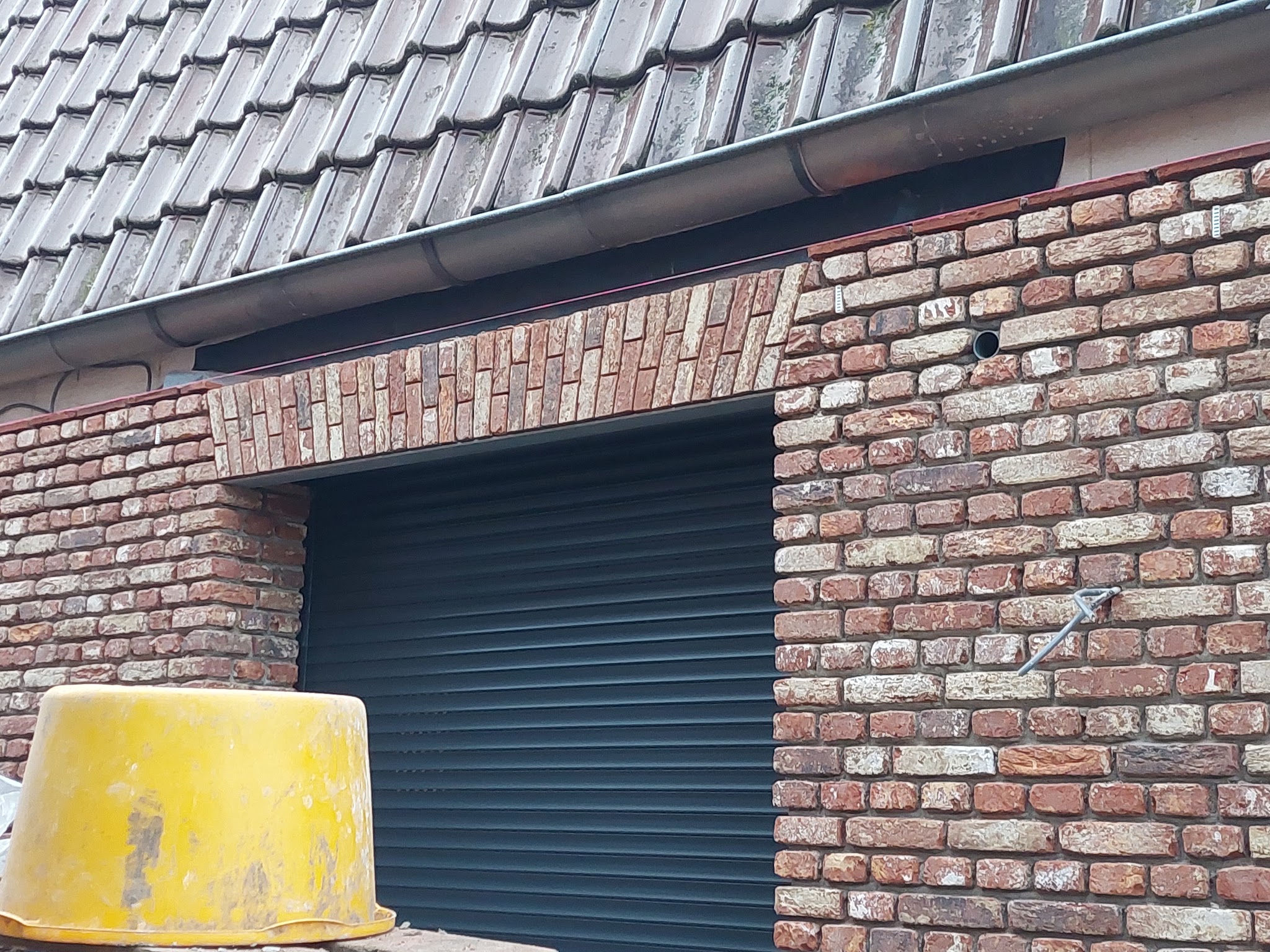 Nieuw gemetselde gevel in oude baksteen rond een garagedeur