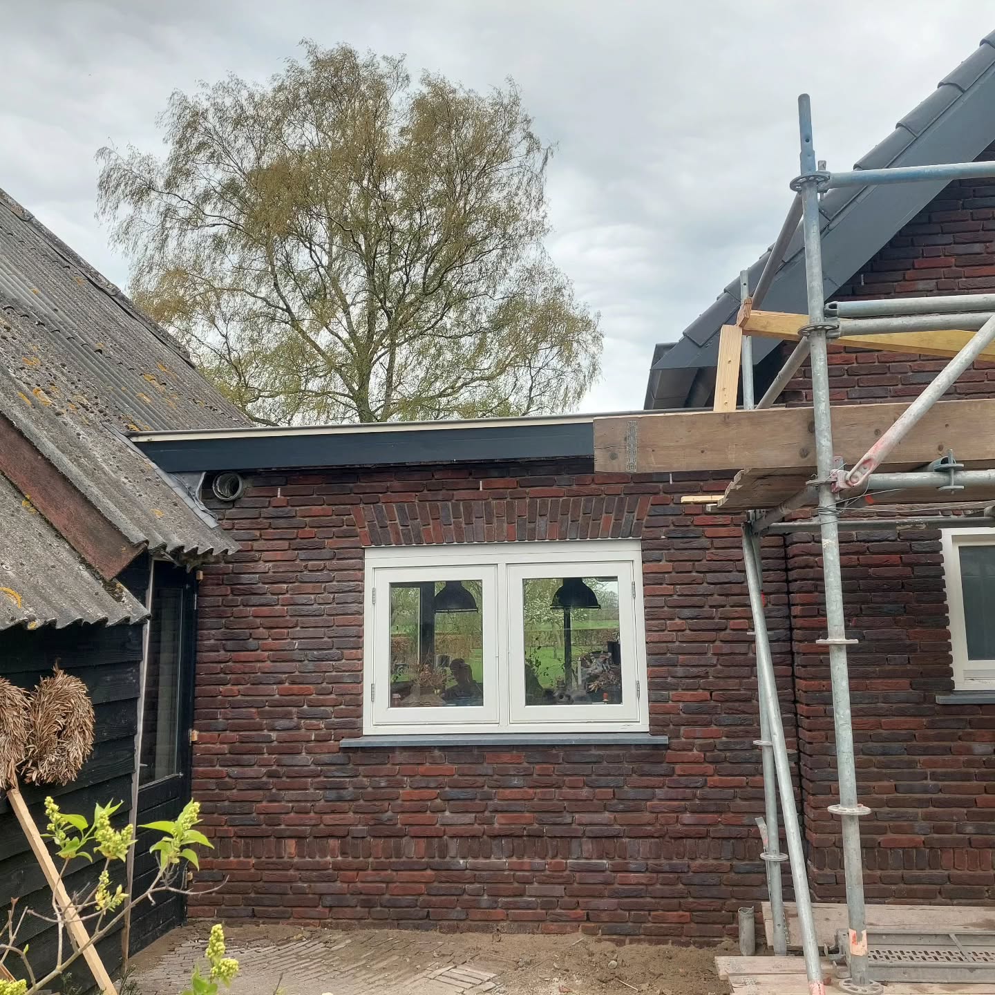 Aanbouw in rode baksteen met steiger ernaast